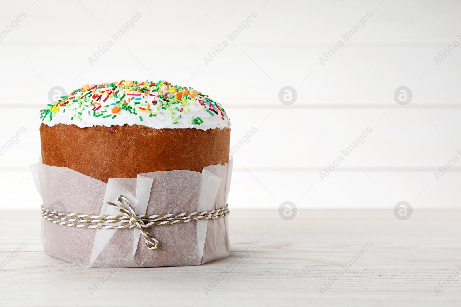 Photo of Traditional Easter cake with sprinkles on white wooden table, space for text