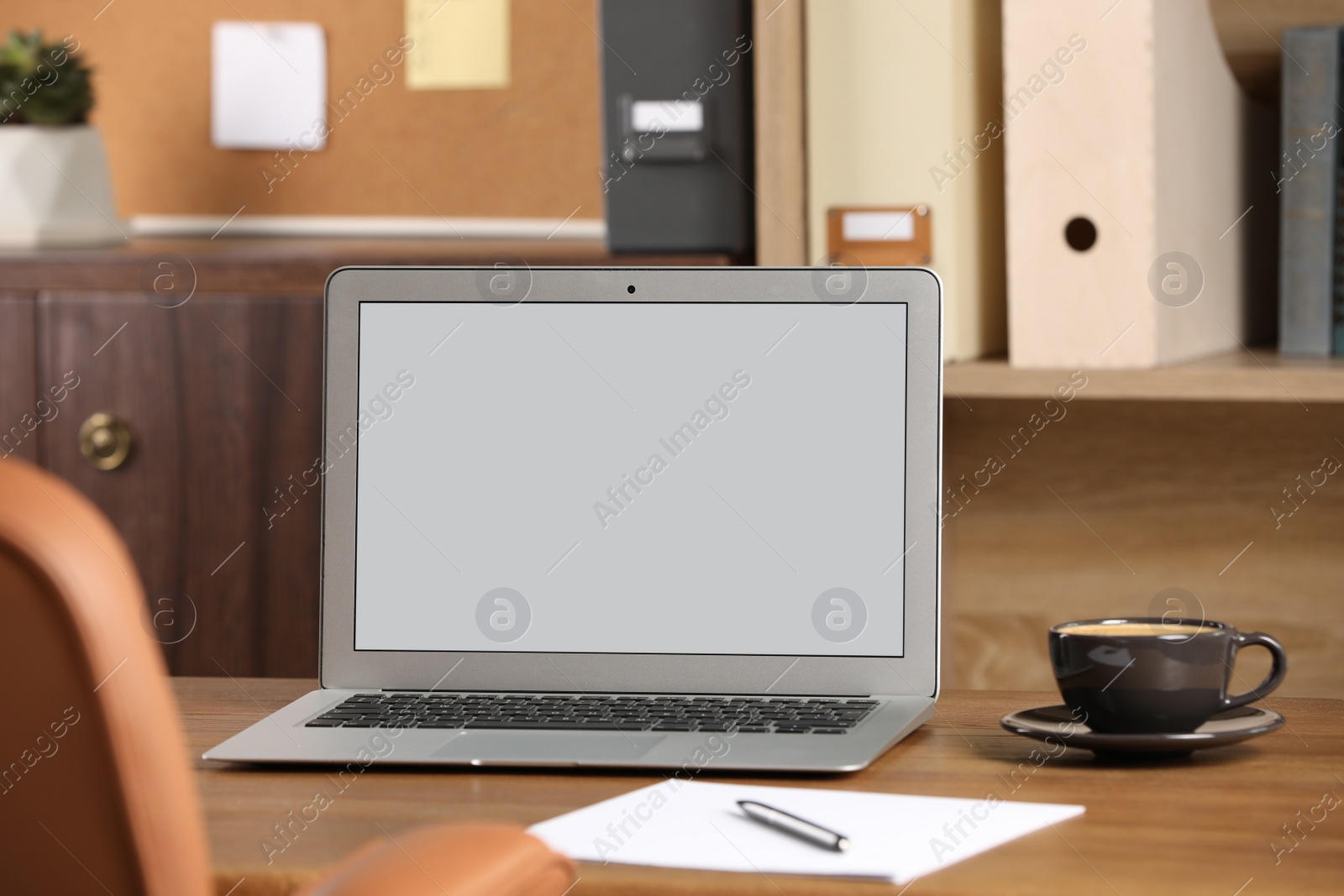 Photo of Modern laptop and cup on table in office