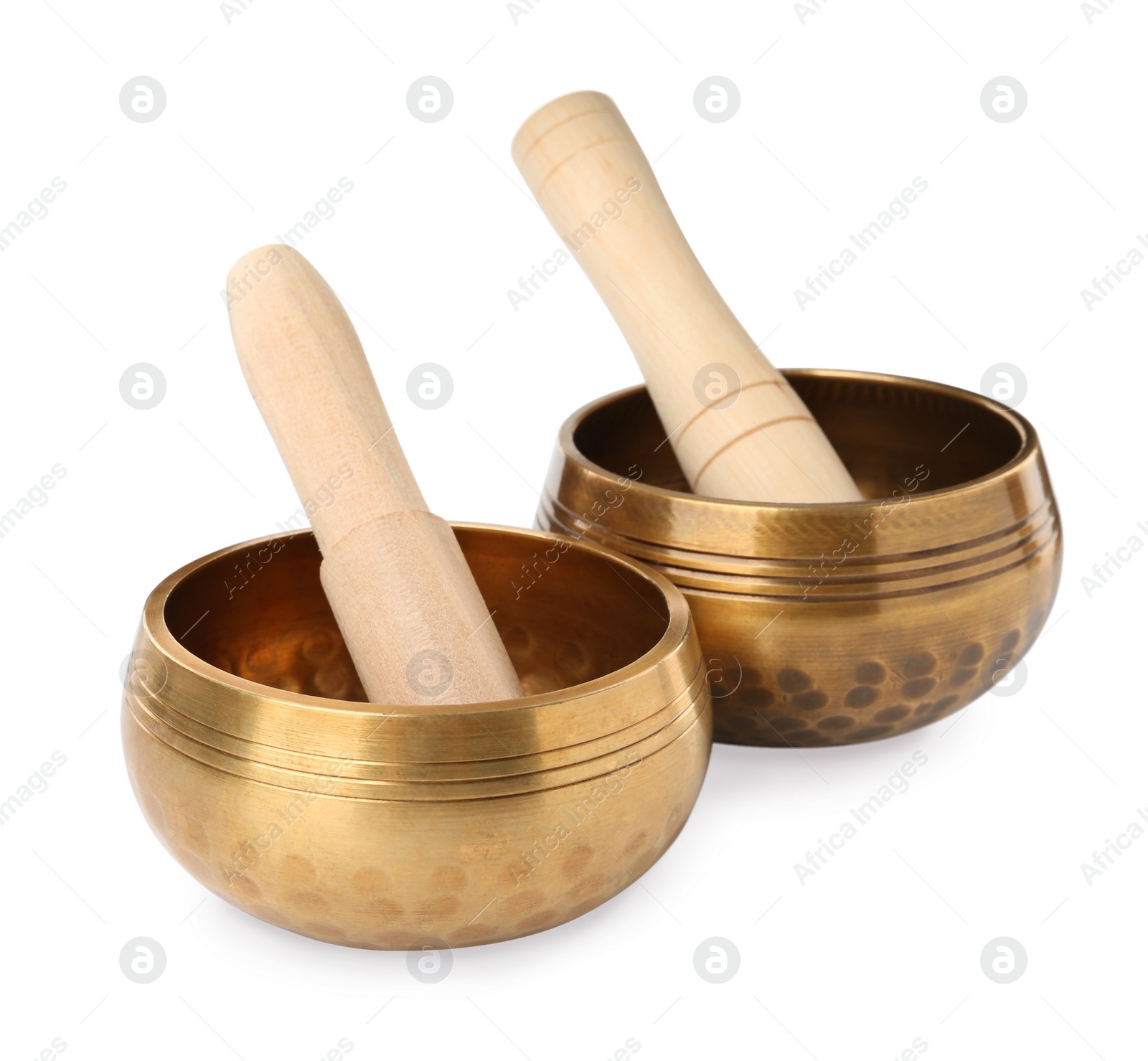 Photo of Golden singing bowls with mallets on white background. Sound healing