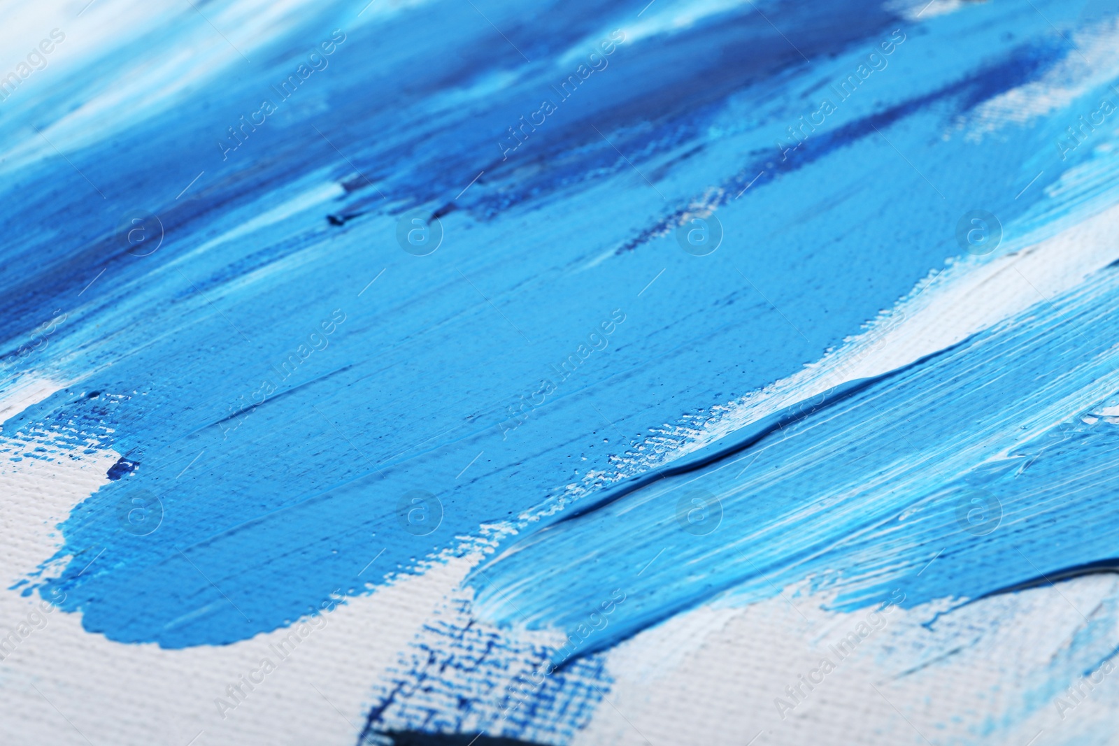 Photo of Beautiful strokes of blue oil paints on white canvas as background, closeup