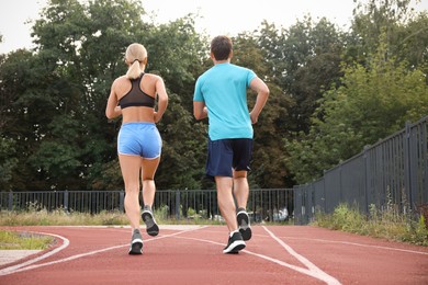 Healthy lifestyle. Sporty couple running at stadium, back view