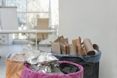 Photo of Full trash cans in modern office, space for text. Waste recycling