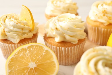Tasty cupcakes with cream and lemon zest on board, closeup