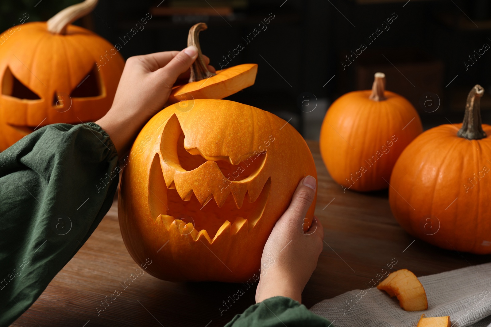 Photo of Woman holding carved pumpkin for Halloween at wooden table, closeup