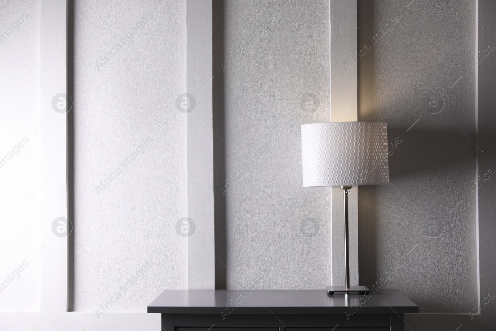 Photo of Wooden table with lamp near white wall in room, space for text