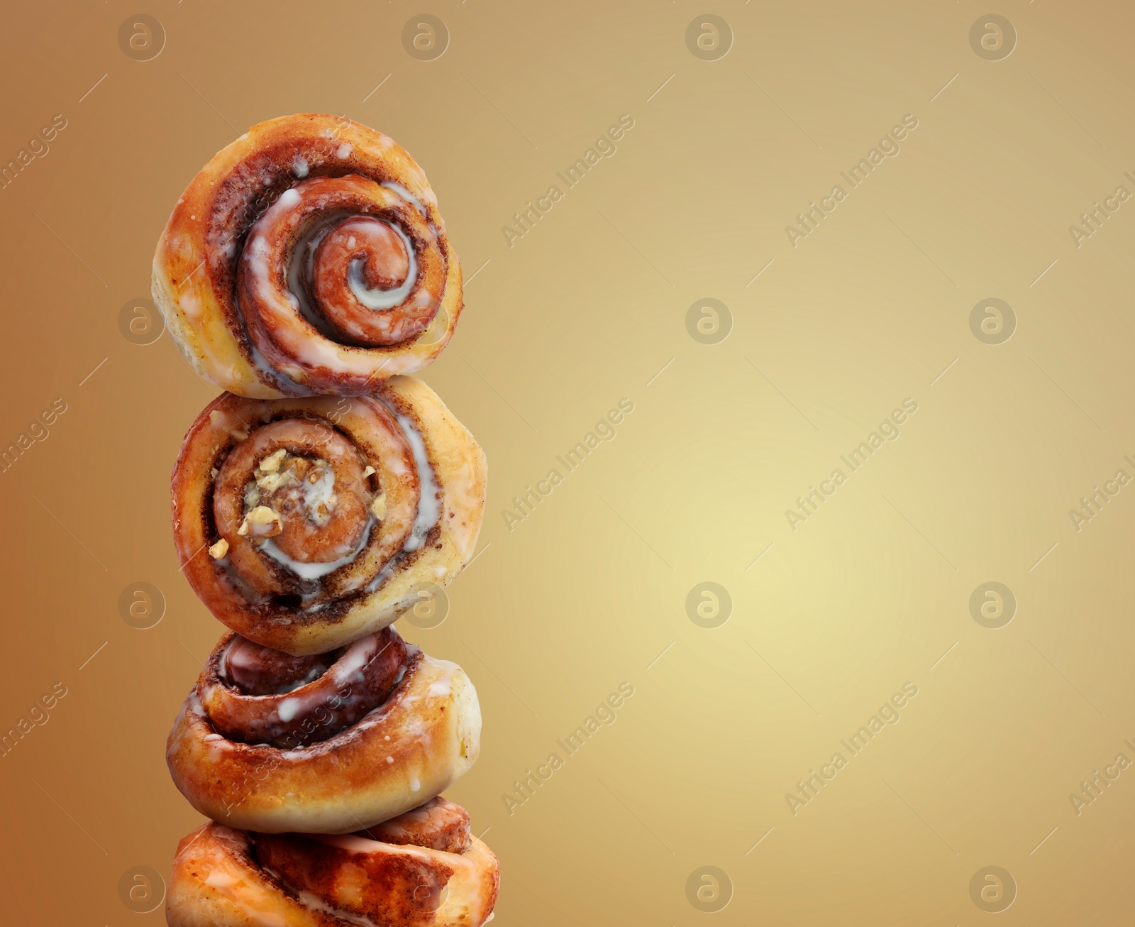 Image of Cinnamon rolls balancing on golden background, space for text