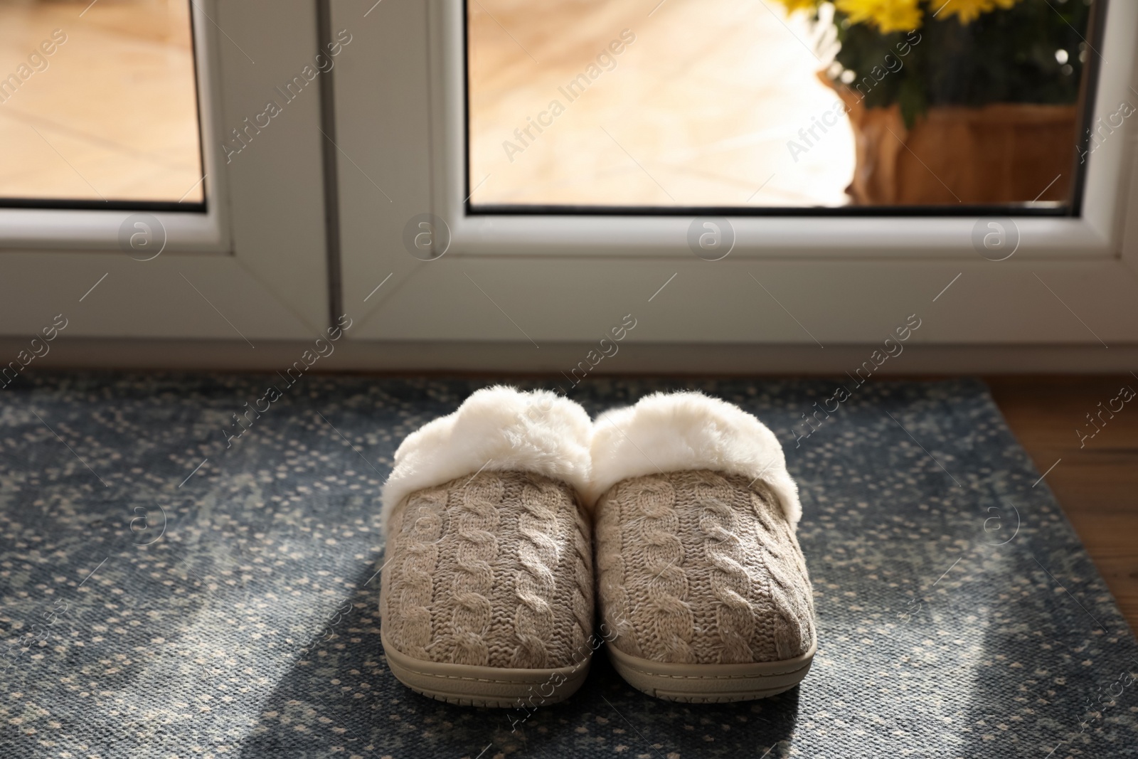 Photo of Pair of beautiful soft slippers on mat in room