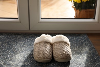 Photo of Pair of beautiful soft slippers on mat in room