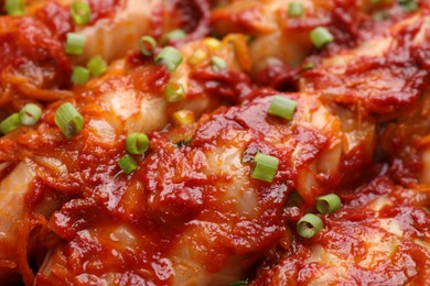 Photo of Delicious stuffed cabbage rolls cooked with homemade tomato sauce as background, closeup