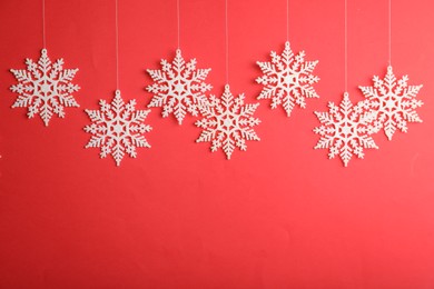 Beautiful decorative snowflakes hanging on red background, space for text