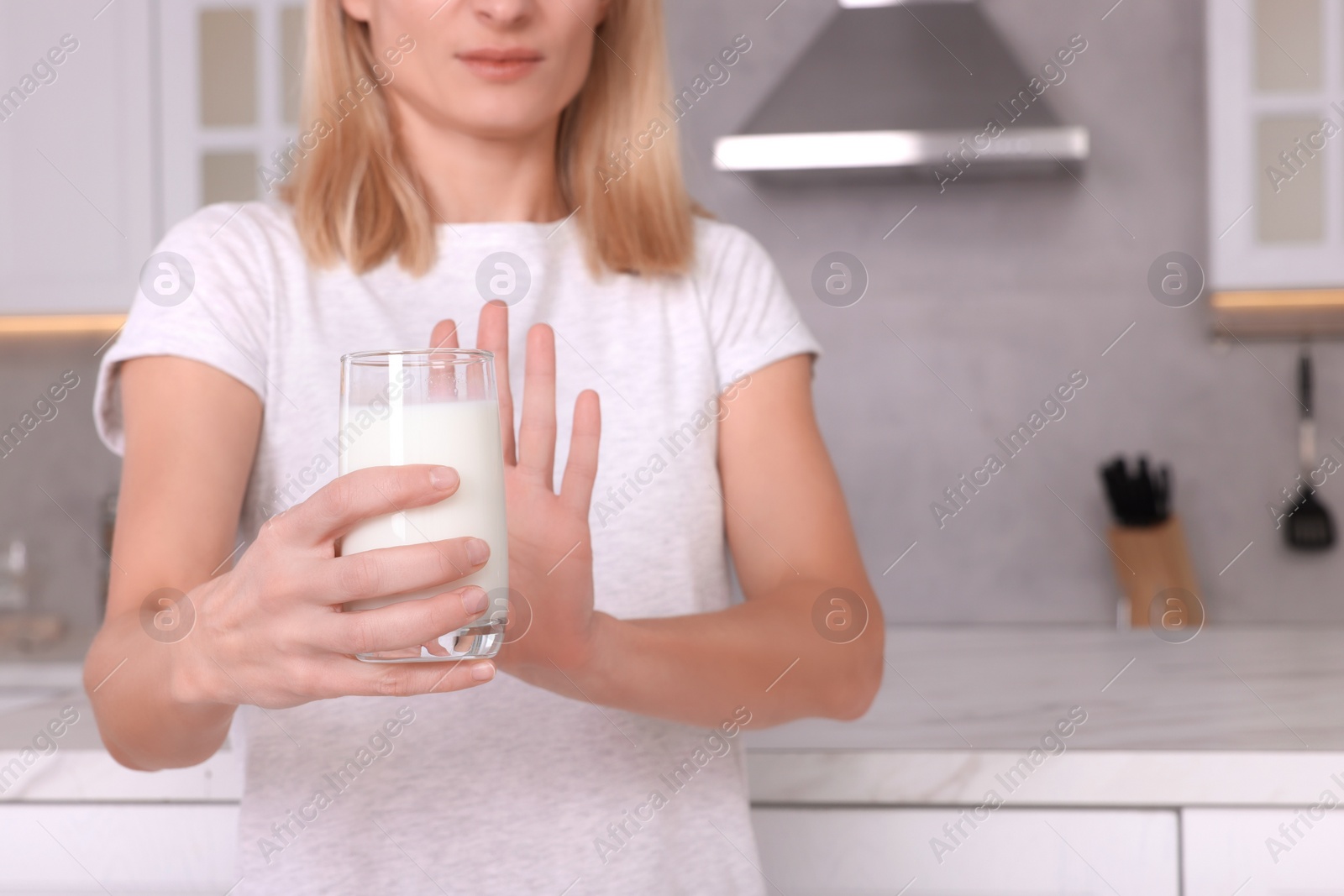 Photo of Woman with glass of milk suffering from lactose intolerance in kitchen, closeup. Space for text