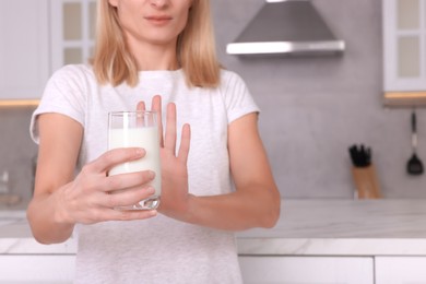 Photo of Woman with glass of milk suffering from lactose intolerance in kitchen, closeup. Space for text