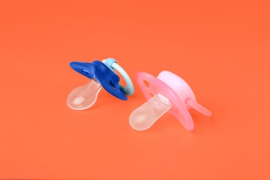 Photo of Colorful baby pacifiers on bright orange background