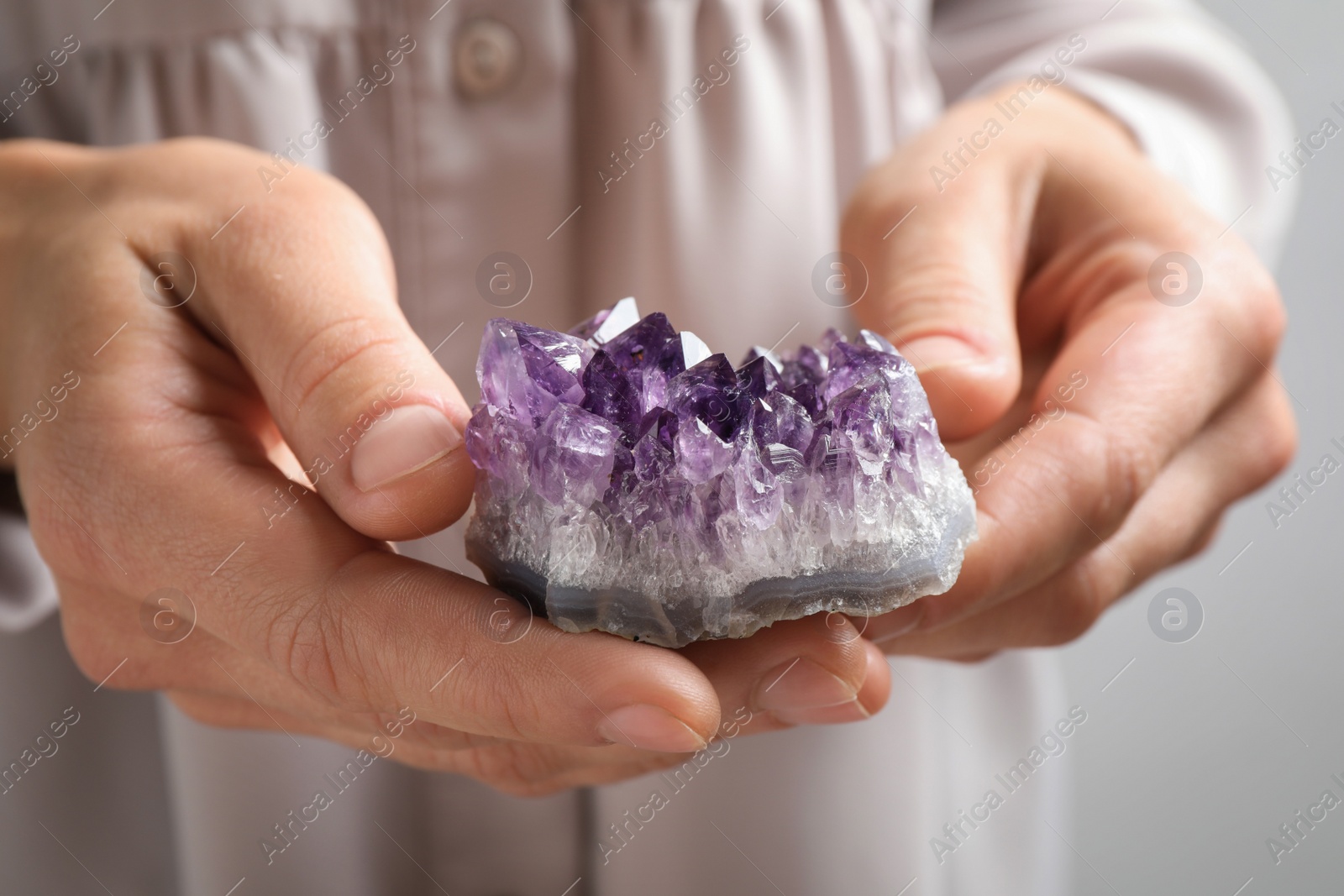 Photo of Young woman holding beautiful amethyst gemstone, closeup