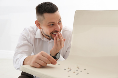 Photo of Man putting pins on chair in office. April fool's day