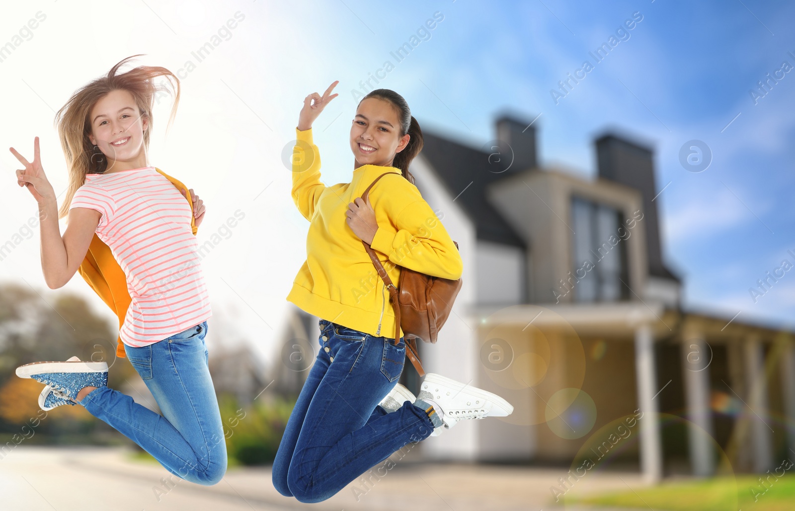 Image of Happy teenage girls jumping near house. School holidays