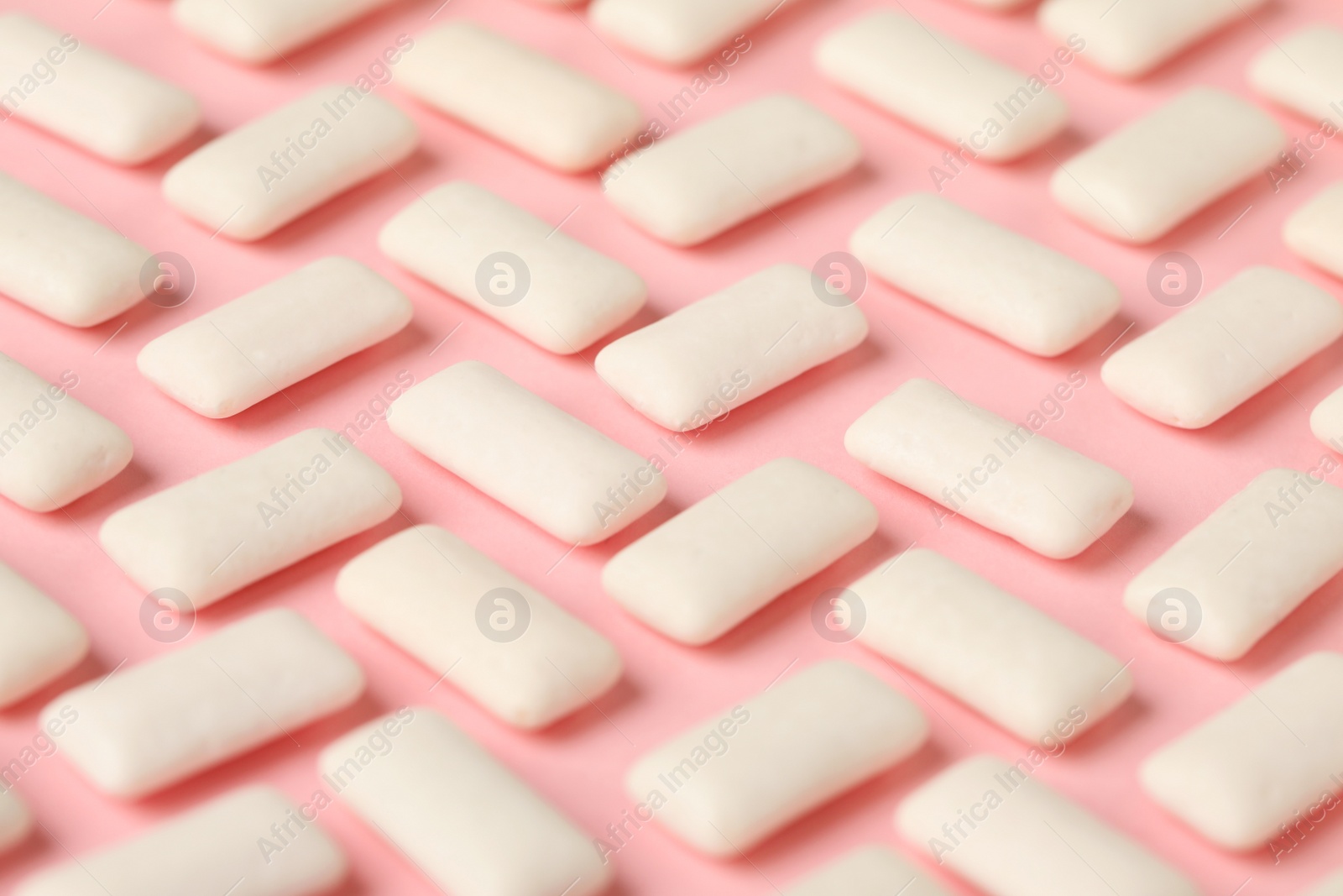 Photo of Many chewing gum pieces on pink background, closeup
