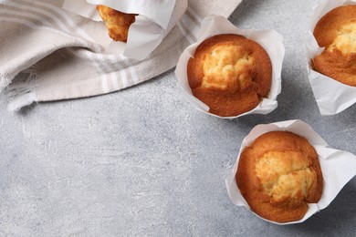 Photo of Delicious sweet muffins on light grey textured table, flat lay. Space for text