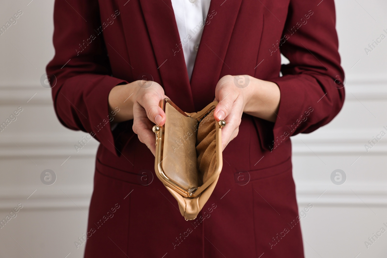 Photo of Woman with empty wallet near white wall, closeup