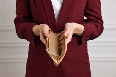 Photo of Woman with empty wallet near white wall, closeup