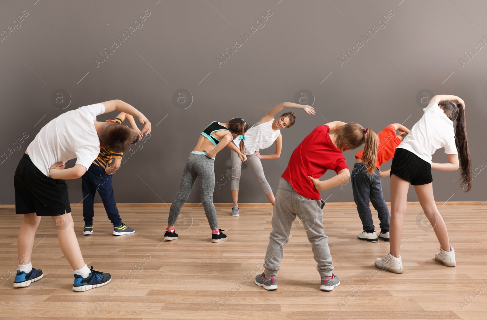 Photo of Cute little children and trainer doing physical exercise in school gym. Healthy lifestyle