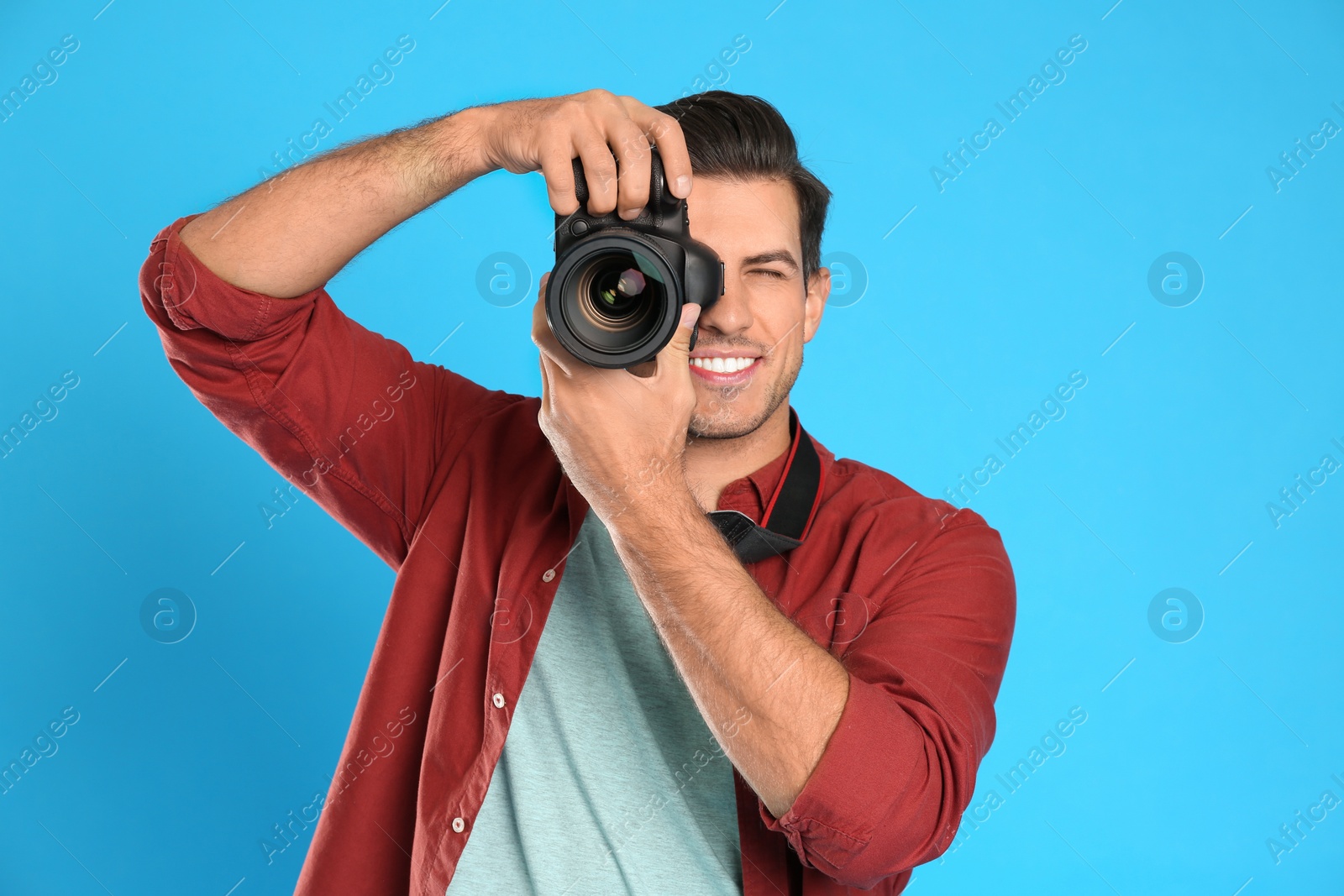 Photo of Professional photographer working on light blue background in studio