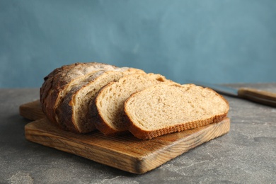 Board with tasty bread on grey table