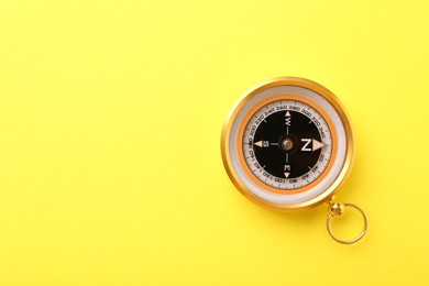 Photo of Compass on yellow background, top view. Space for text