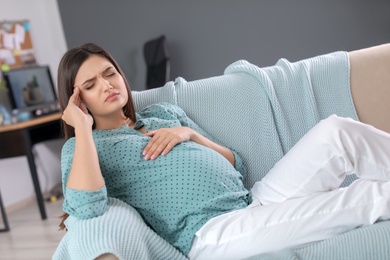 Young pregnant woman suffering from headache at home