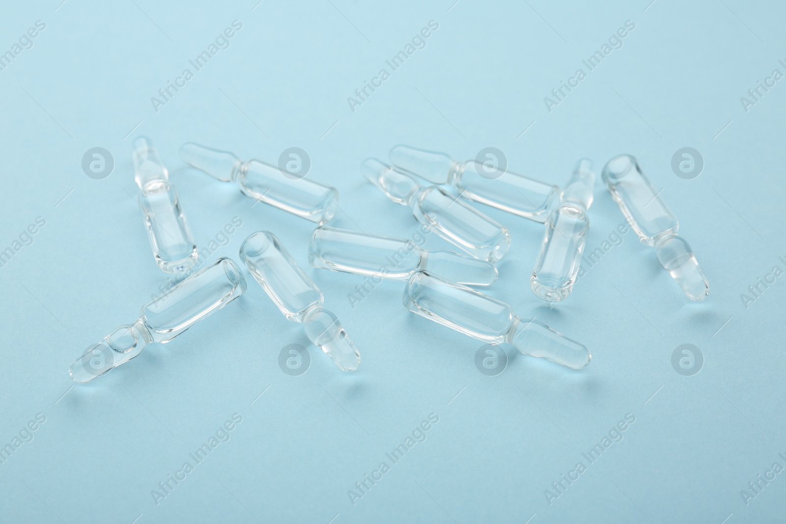 Photo of Glass ampoules with liquid on light blue background