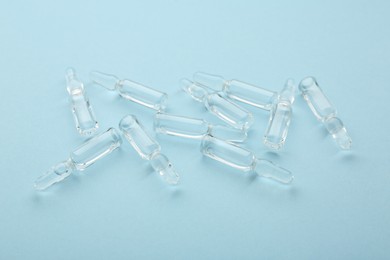 Photo of Glass ampoules with liquid on light blue background