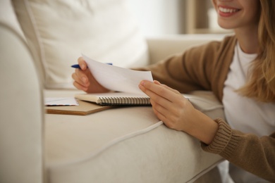 Photo of Happy woman writing letter on sofa at home, closeup