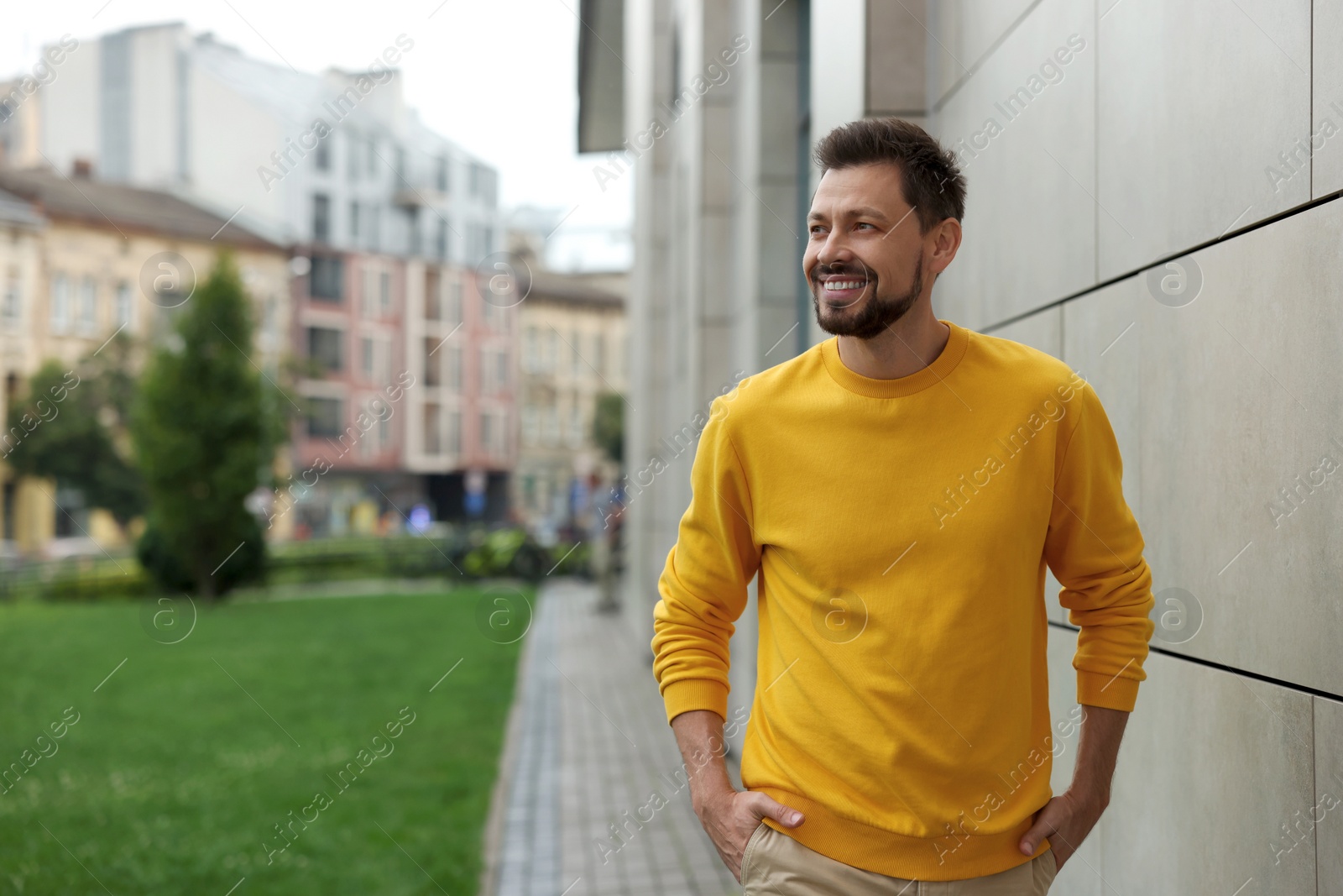 Photo of Handsome bearded man walking on city street, space for text