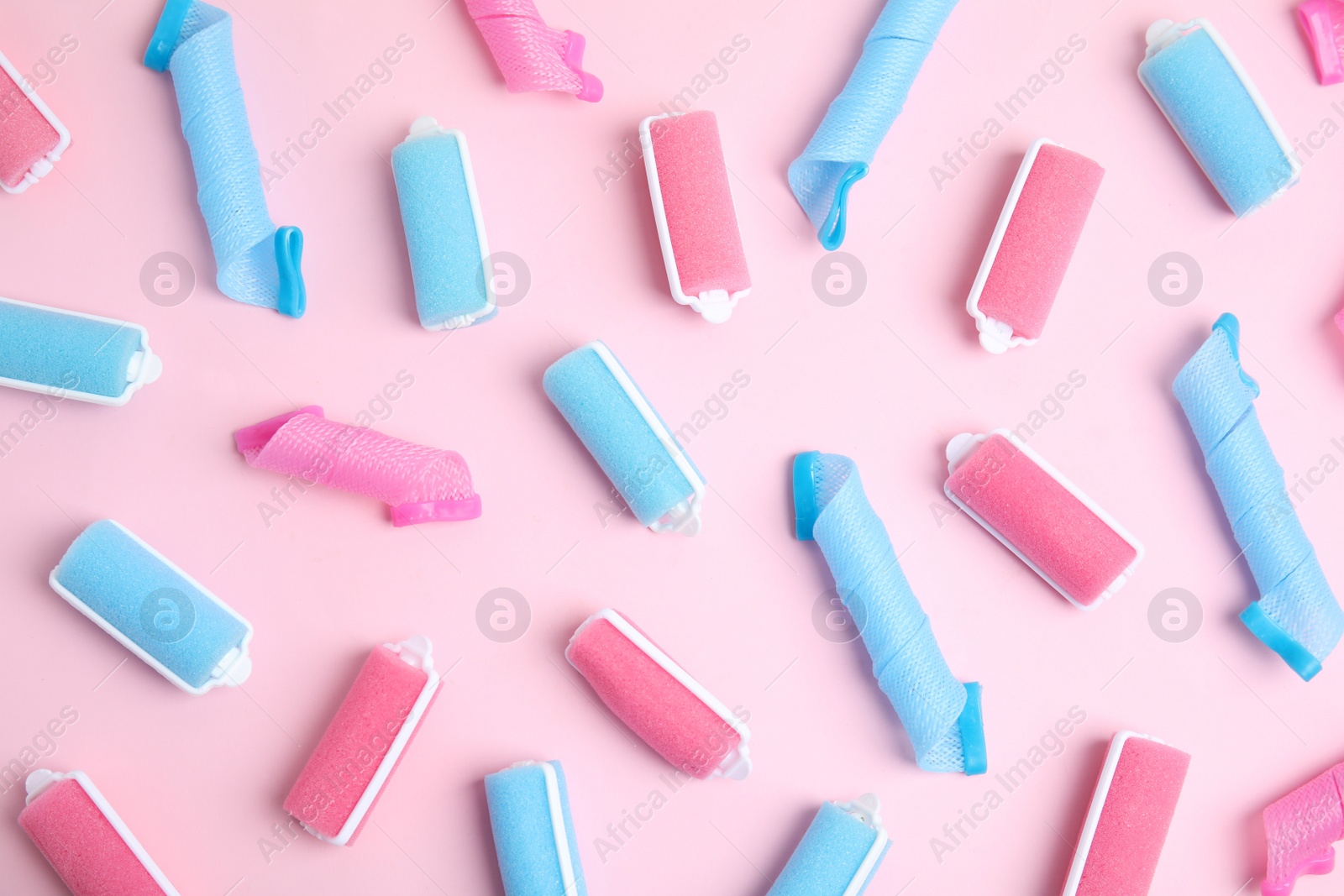 Photo of Different hair curlers on pink background, flat lay. Styling tool