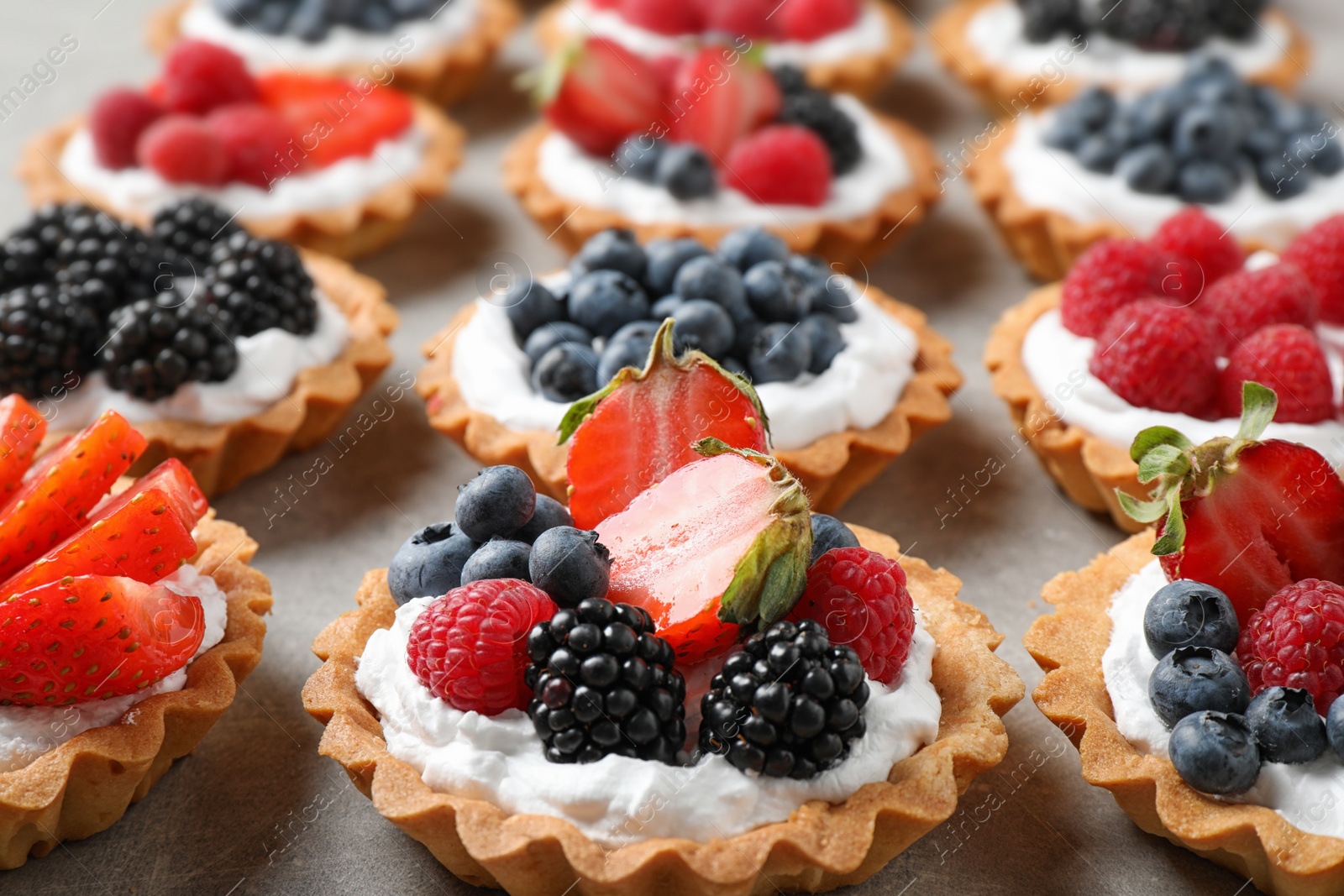 Photo of Many different berry tarts on table. Delicious pastries