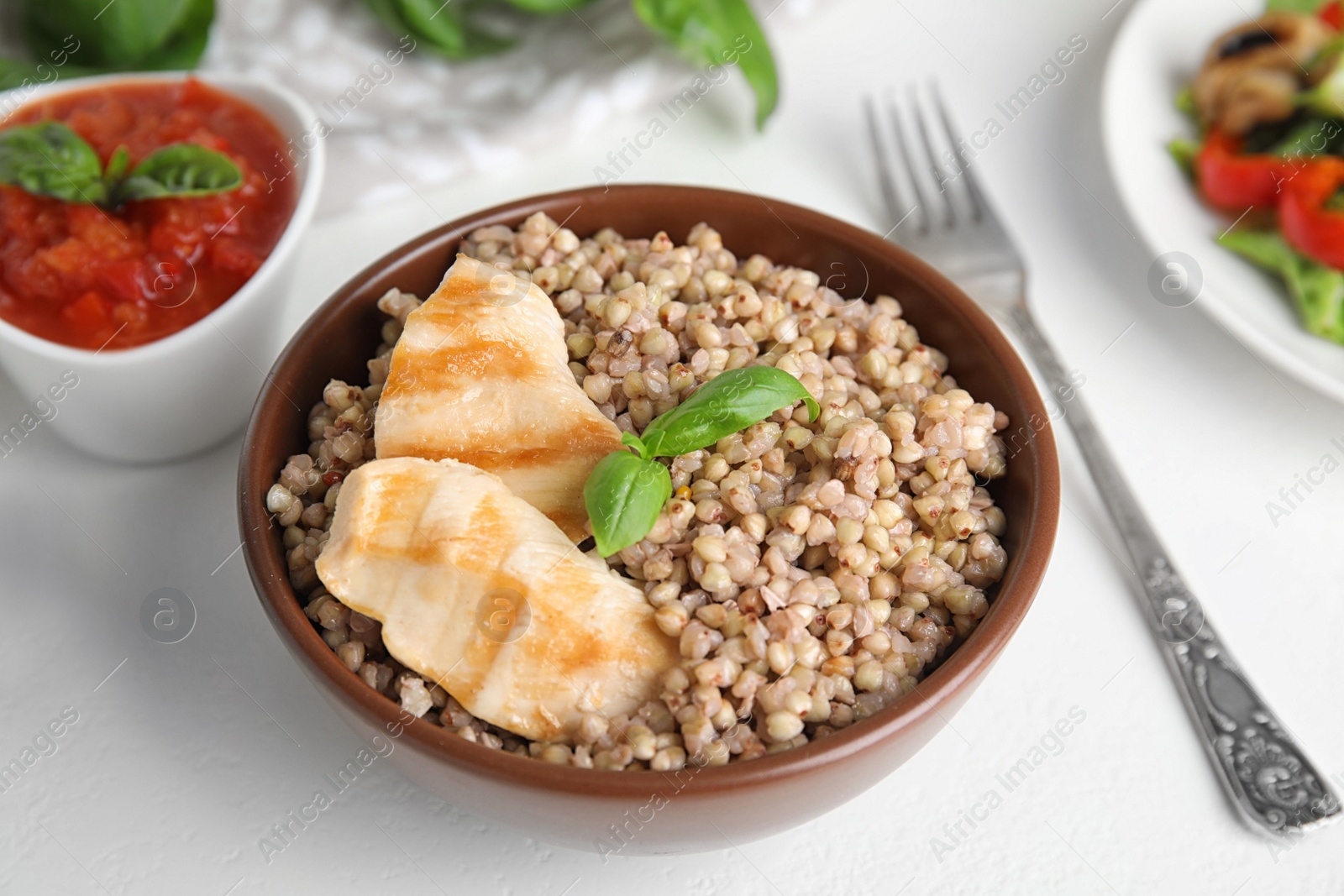 Photo of Tasty buckwheat porridge with meat on white table