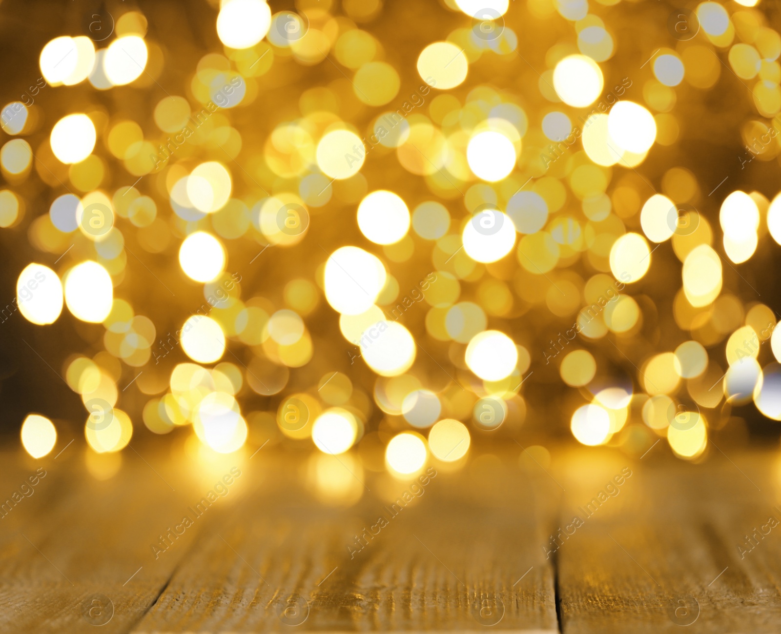 Image of Blurred view of gold lights and wooden table, bokeh effect