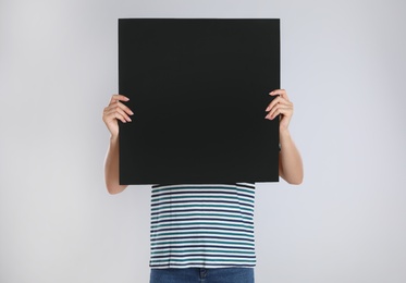 Woman holding blank poster on light grey background