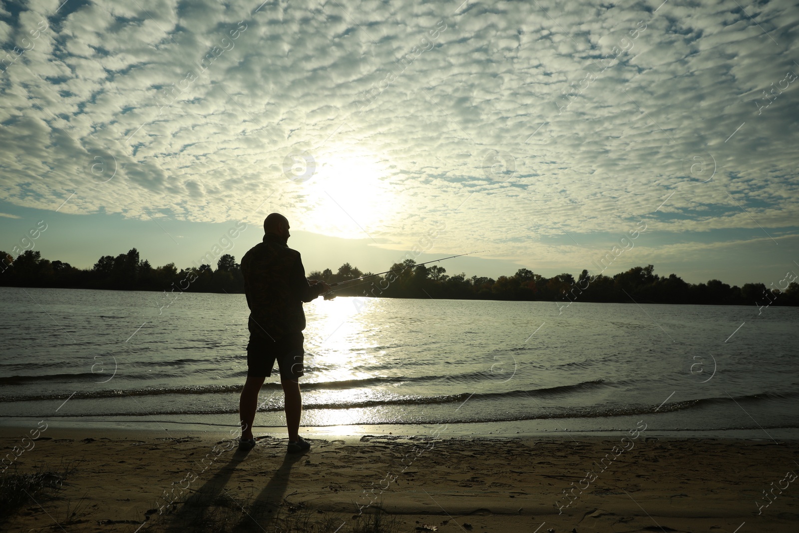 Photo of Fisherman with rod fishing at riverside, space for text