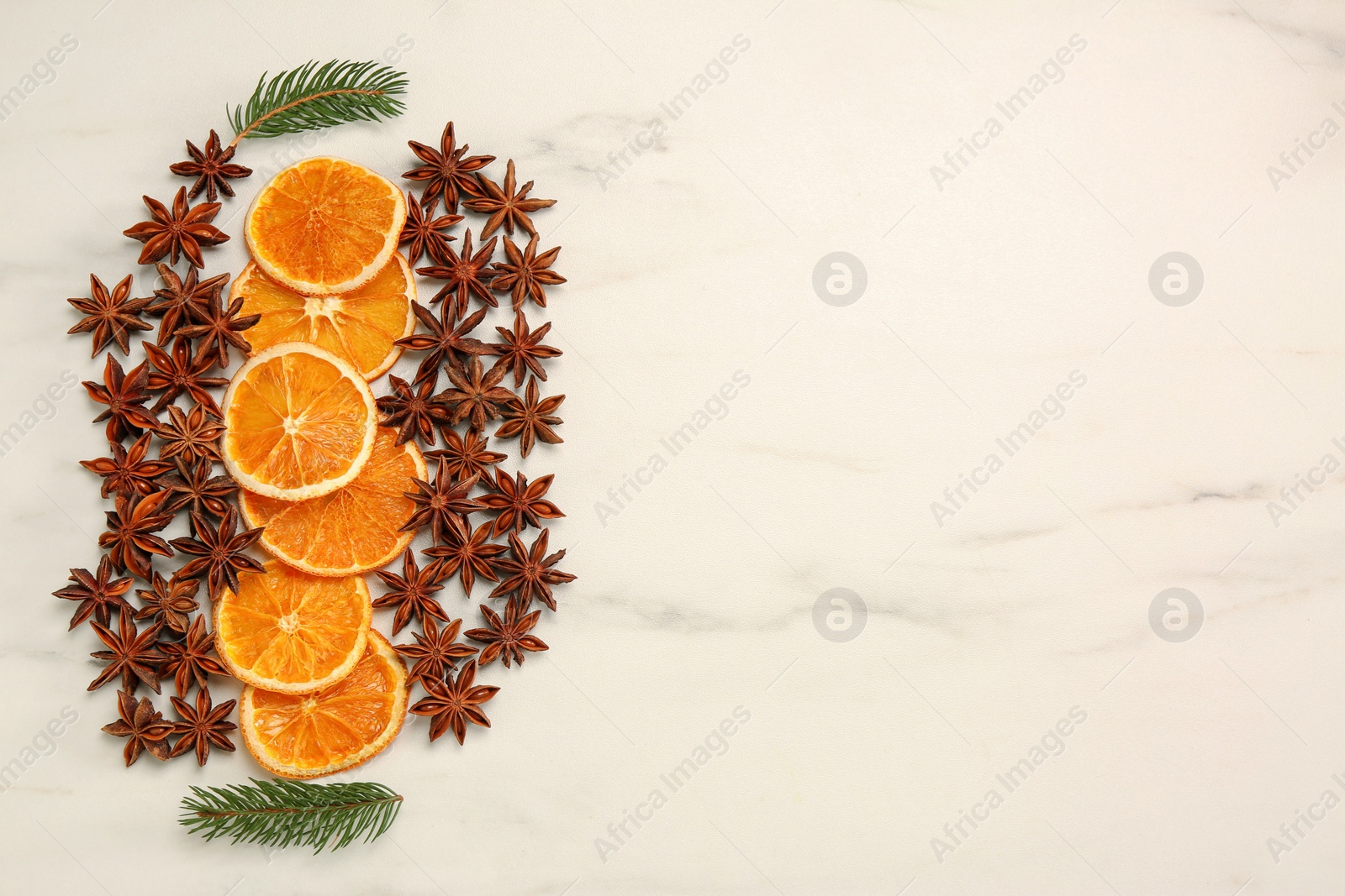 Photo of Dry orange slices, anise stars and fir branch on white marble table, flat lay with space for text