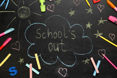 Photo of Pieces of color chalk and stationery on blackboard with text School's Out, flat lay. Summer holidays