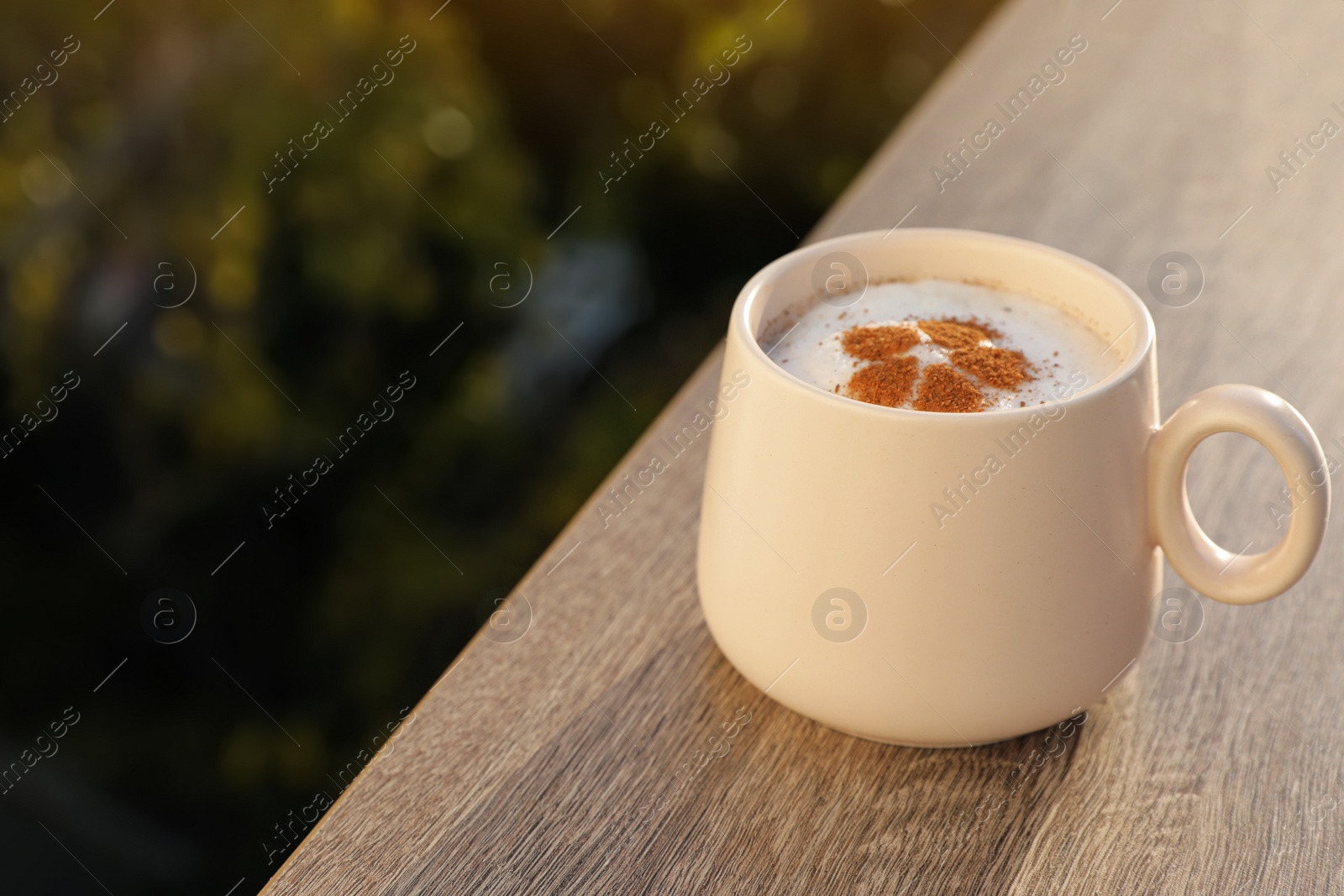 Photo of Ceramic cup of aromatic coffee with foam on wooden table. Space for text