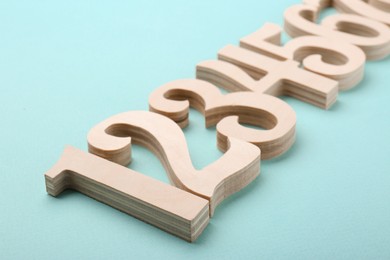 Photo of Wooden numbers on light background, closeup view