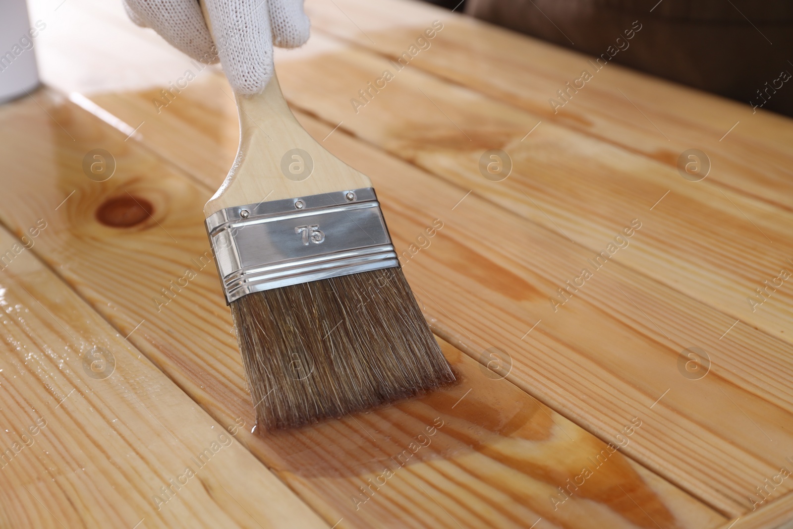 Photo of Man varnishing wooden surface with brush, closeup