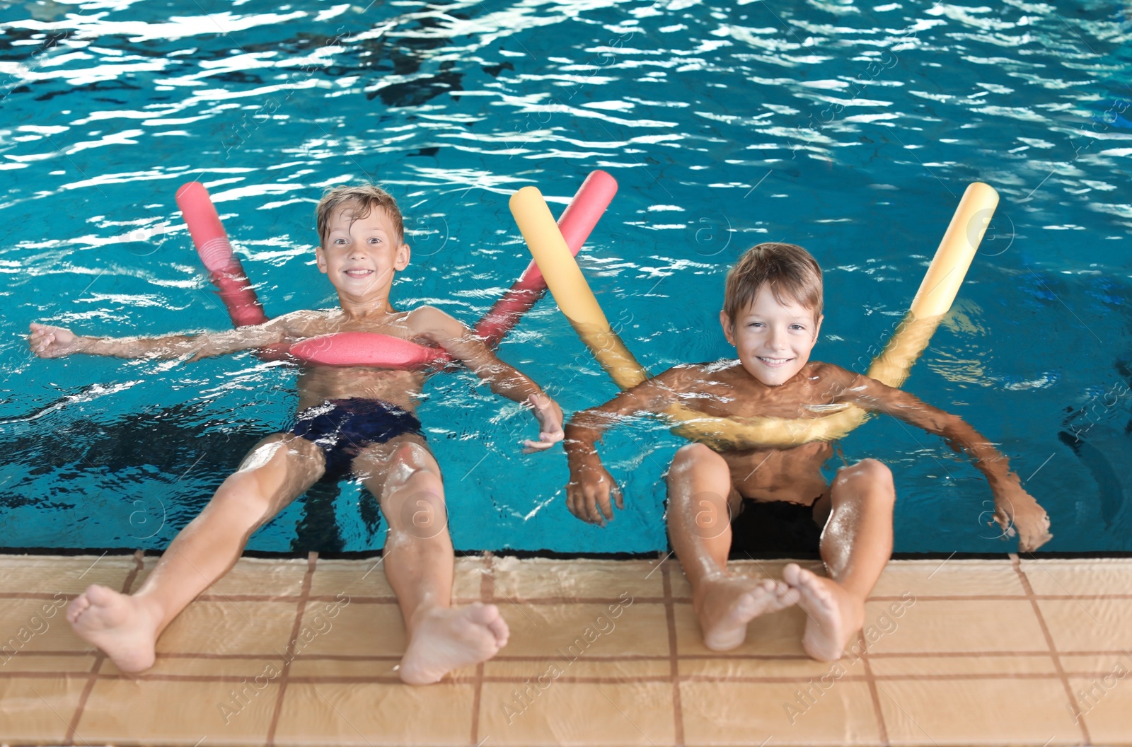 Photo of Little boys with swimming noodles in indoor pool