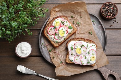 Delicious sandwiches with radish, egg, cream cheese and microgreens on wooden table, flat lay