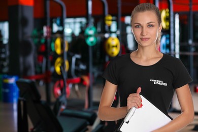 Image of Portraitprofessional personal trainer with clipboard in gym. Space for text