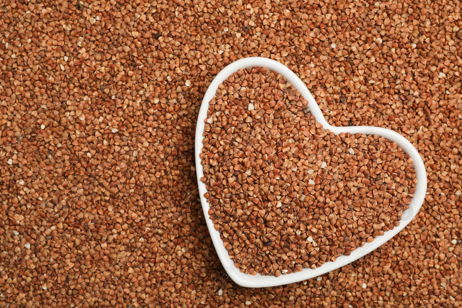 Photo of Heart shaped plate with buckwheat on grains, top view. Space for text