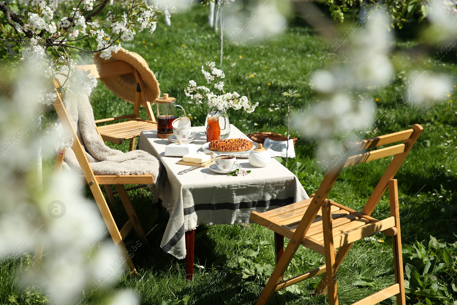 Photo of Beautiful table setting with spring flowers in garden on sunny day