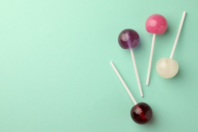 Photo of Tasty lollipops on turquoise background, flat lay. Space for text